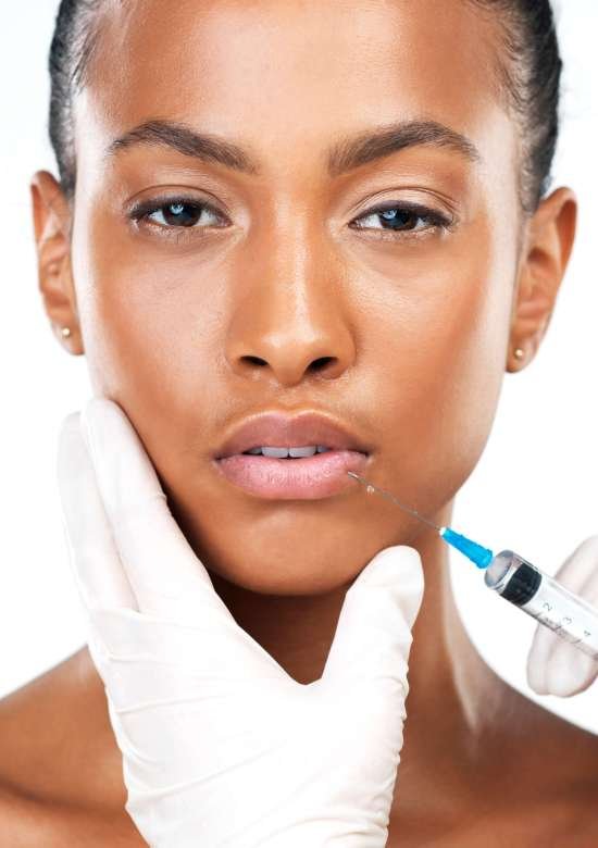 Black woman, portrait and injection for plastic surgery with cosmetics, facial change and skincare in studio. African client, hands and needle for lips, collagen filler and beauty by white background.