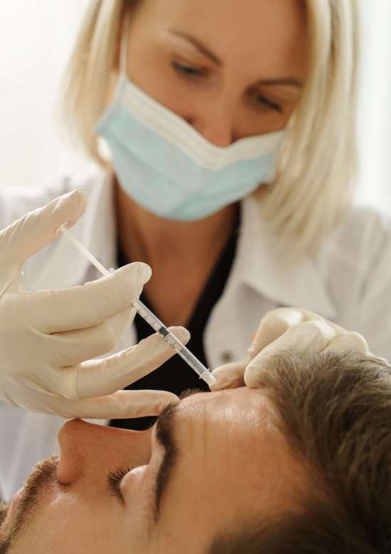 Female doctor and male client during filler injections in aesthetic medical clinic